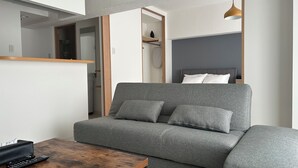 A modern living room with a grey sofa, a wooden coffee table, and a hanging pendant light. - TOWN ROYAL 601 (Sapporo)