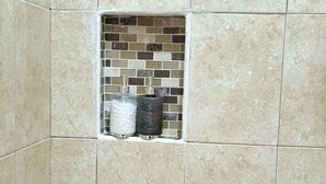 Une salle de bain avec des carreaux de couleur beige et un petit motif décoratif en mosaïque.