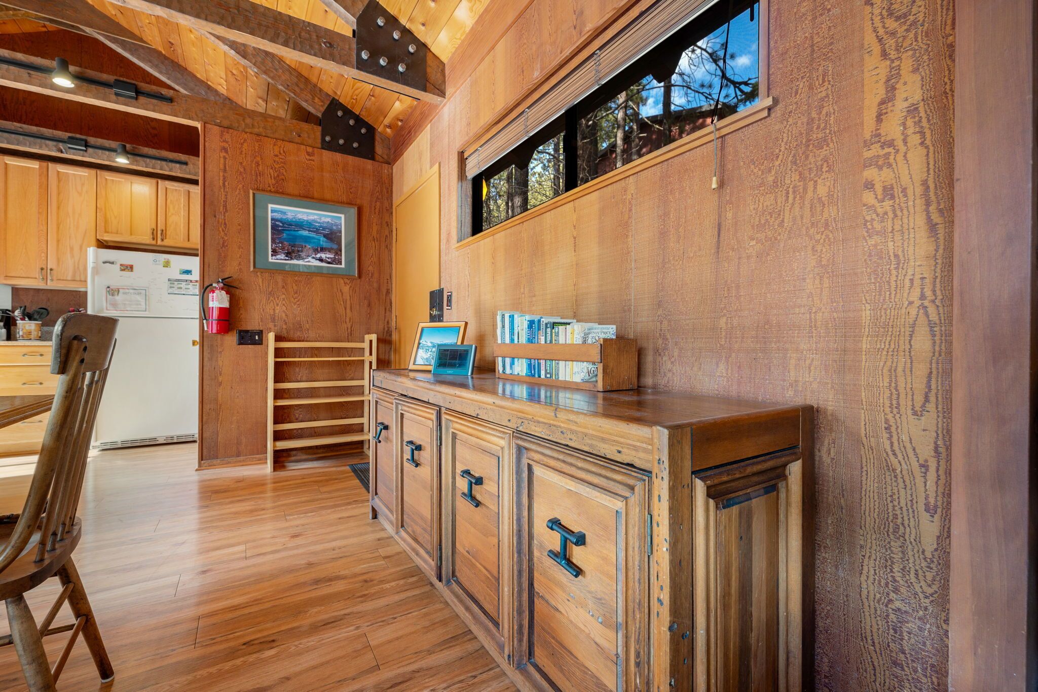 Un interior de madera con una zona de cocina, armarios de madera y una estantería empotrada.