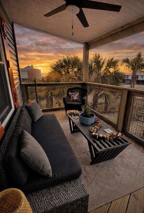 A balcony with a sofa, a chair, a table, and a ceiling fan. - New St George Island Beach Rental Private Pool (Heated or Cooled for a fee), Golf Cart Included, Pet Friendly, Direct Beach Access Mini Putt-Putt Golf (Saint George Island)