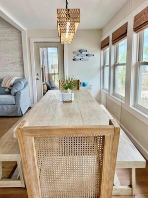 A spacious dining area with a wooden table, a woven chair, and a hanging light fixture. - New St George Island Beach Rental Private Pool (Heated or Cooled for a fee), Golf Cart Included, Pet Friendly, Direct Beach Access (Saint George Island)