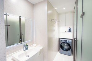 Ein modernes Badezimmer mit Waschbecken, Spiegel und Waschmaschine.