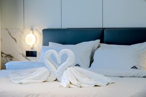 Ein Hotelzimmer mit einem Bett, weißen Handtüchern, die zu einem Herz geformt sind, und einer Wandleuchte.