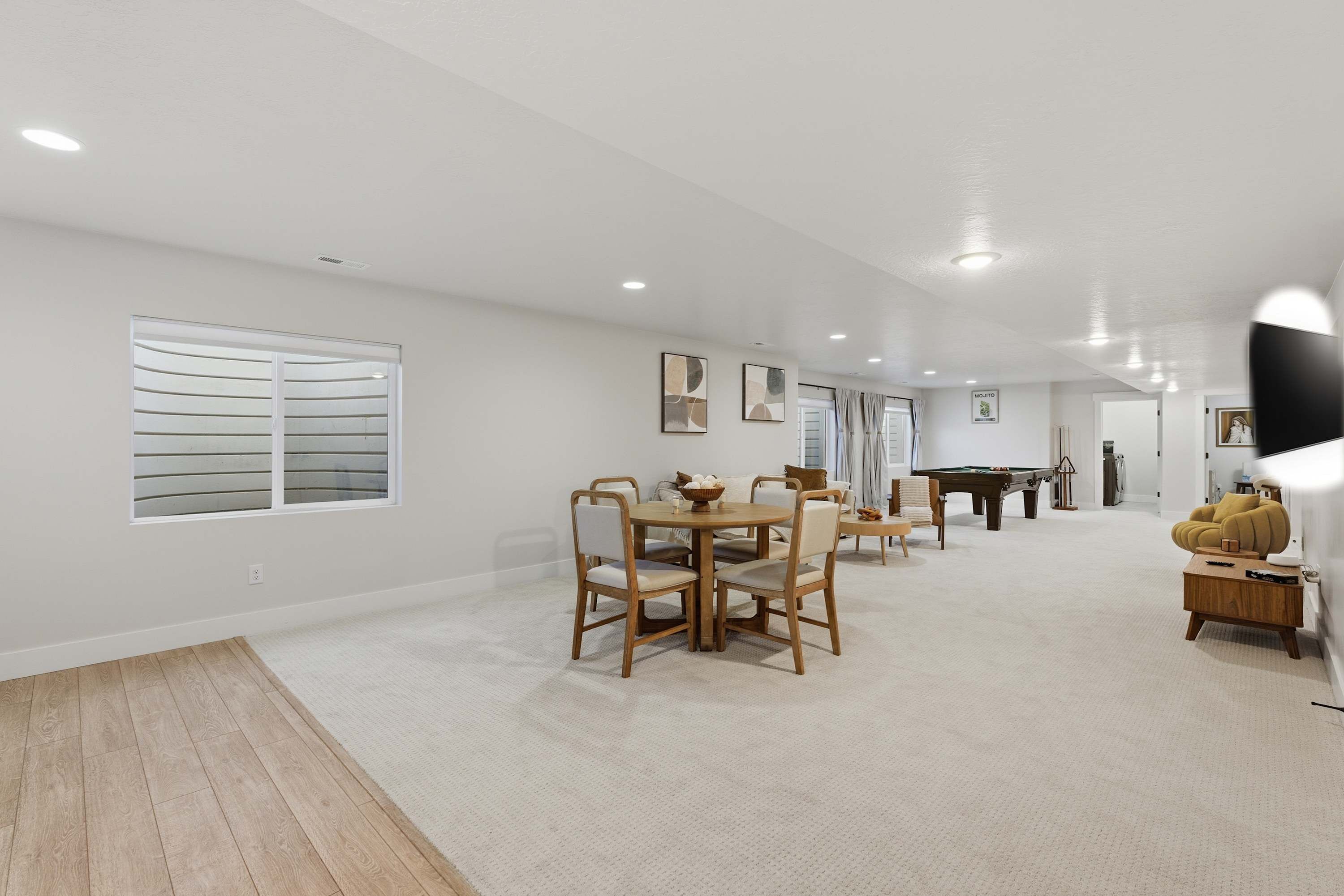 A spacious living room with a dining area, a pool table, and a sofa.