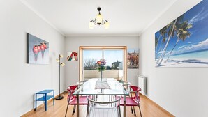 A dining room with a glass table, red chairs, and artwork on the walls. - GuestReady - Charming Porto retreat with terrace (Boavista)