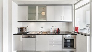 A modern kitchen with stainless steel appliances, a built-in oven, and a large window. - GuestReady - Charming Porto retreat with terrace (Boavista)