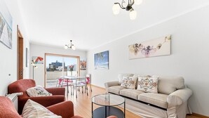 A modern living room with a sofa, armchairs, a glass coffee table, and a dining area with a table and chairs. - GuestReady - Charming Porto retreat with terrace (Boavista)