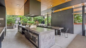 A modern kitchen with a large island, built-in oven, and a gas range. - Bright 2-Bed Apartment in Bowen Hills (Bowen Hills)