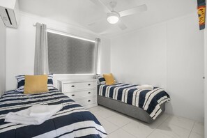 A bedroom with two beds, a window with curtains, a ceiling fan, and a white dresser. - Lindomare 16 | Kings Beach Ocean Views, Pool & Walk Everywhere (Kings Beach)