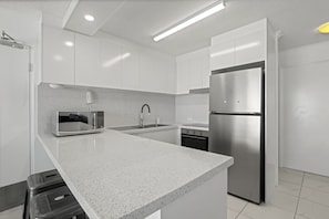 A modern kitchen with white cabinetry, a stainless steel refrigerator, a microwave, and a gas stove. - Lindomare 16 | Kings Beach Ocean Views, Pool & Walk Everywhere (Kings Beach)
