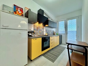 A modern kitchen with a refrigerator, stove, and sink. There is a window with a view of the outside. - " Maison de Charme " (Bari Sardo)