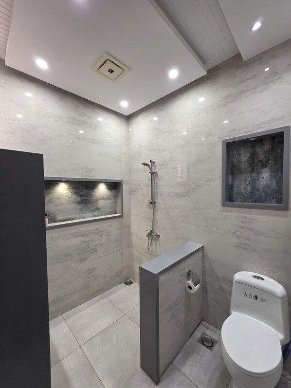 A modern bathroom with a shower, toilet, and a built-in vanity.