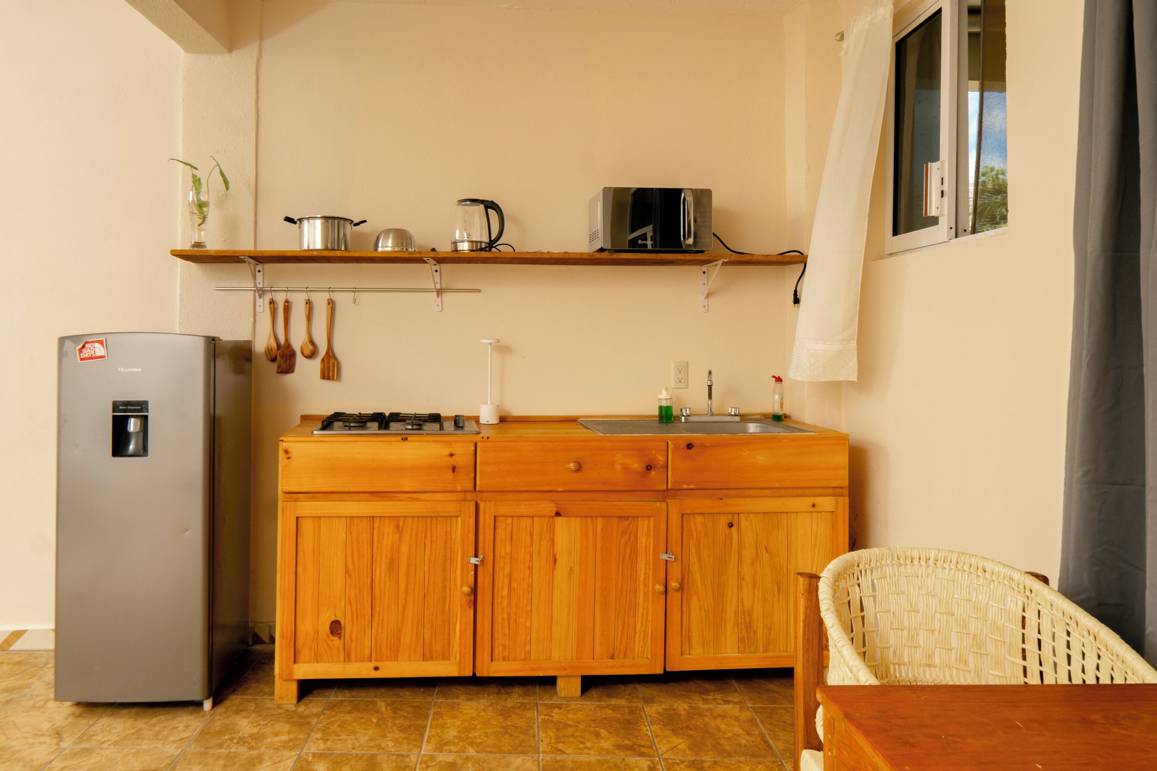 A compact kitchen with wooden cabinets, a built-in microwave, and a refrigerator.
