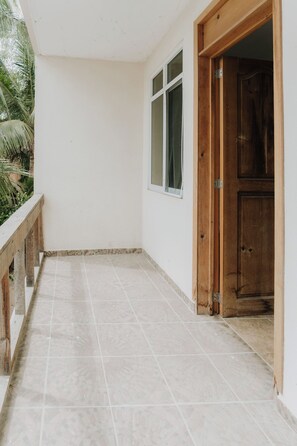 A corridor with tiled flooring, a wooden door, and a window.
