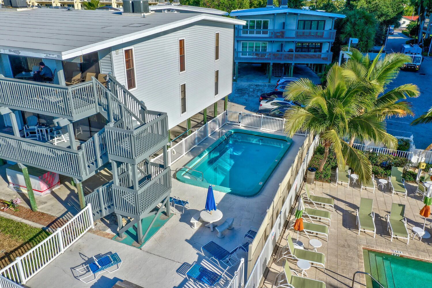 A multi-story building with a rooftop pool, outdoor seating, and a view of the ocean.