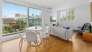 Ein modernes Wohnzimmer mit Essbereich, großen Fenstern und einem grauen Sofa.