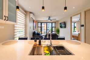 Une cuisine moderne dotée d’un îlot central, d’un évier intégré et d’un ventilateur de plafond.
