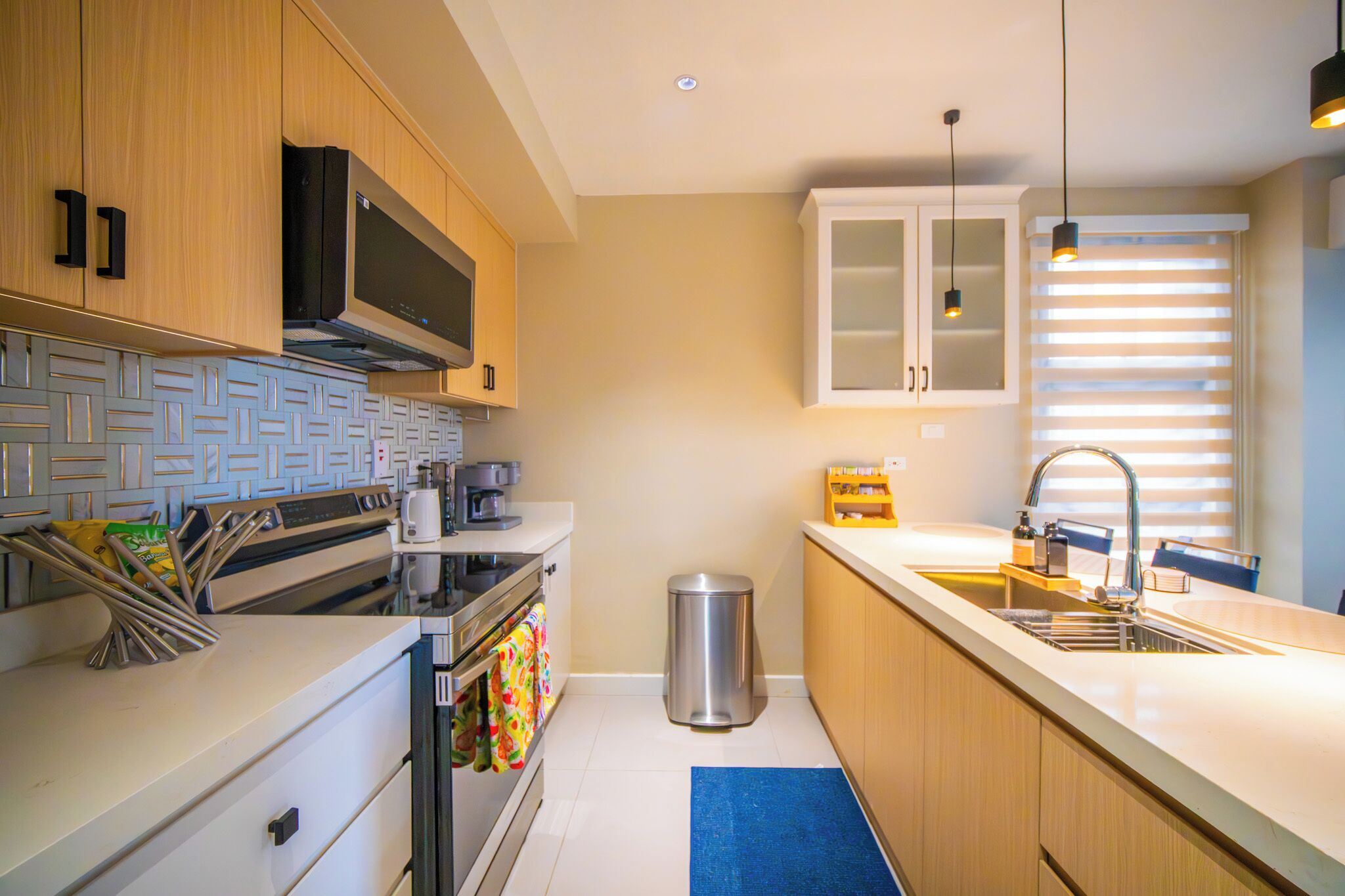 A modern kitchen with wooden cabinets, a stainless steel sink, and a blue mat.