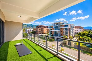 Un balcon avec du gazon synthétique, un tapis de yoga et une bouteille d’eau.