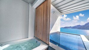 Ett modernt badrum med ett bubbelbadkar, träpanel och utsikt över havet.