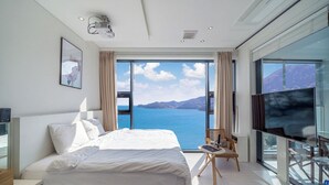 Ett modernt sovrum med en stor säng, en tv och utsikt över havet.