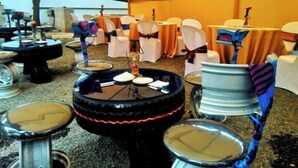 Un espace événementiel extérieur aménagé avec des tentes, comprenant des tables rondes, des chaises et un élément décoratif central.