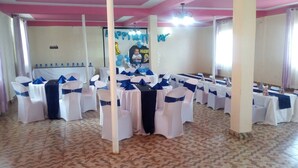 Une salle de banquet avec des tables et des chaises disposées pour un événement.