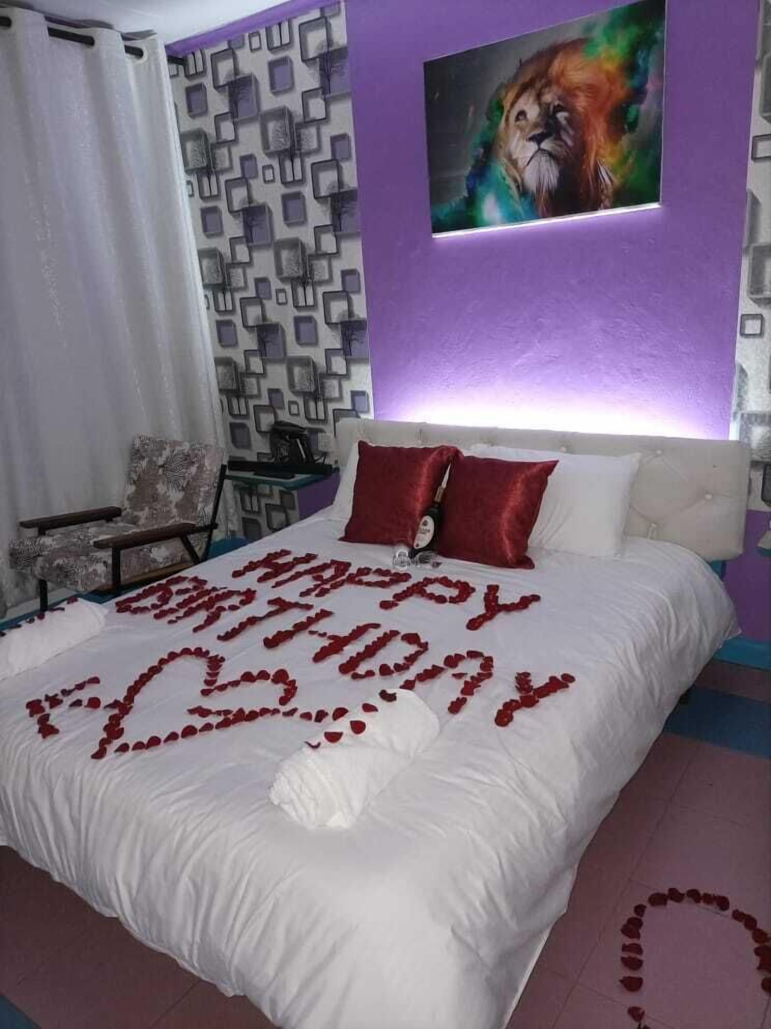 A bedroom with a bed, a pillow, a wall with a geometric pattern, and a painting of a lion.