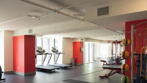 Un gimnasio amplio con cintas de correr, pelotas de ejercicio y una pared roja.