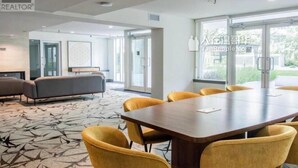 Una sala de conferencias moderna con una mesa grande y sillas amarillas, un sofá y un ventanal con vistas a zonas verdes.