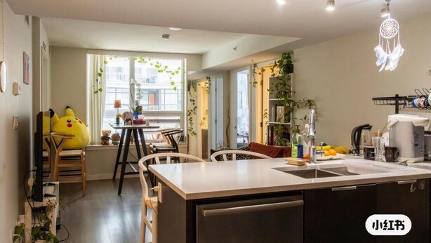 Una cocina moderna con una isla central, comedor con sillas y un amplio ventanal con cortinas.