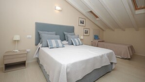 A bedroom with a large bed, a bedside table, a lamp, and a small table with a phone. - MARINAZZURRA  - Goelba (Porto Azzurro)