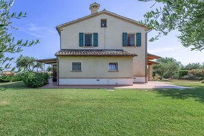 A two-story house with a tiled roof, a small balcony, and a well-maintained lawn.