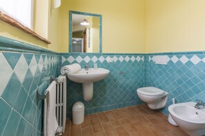 A bathroom with a sink, toilet, and bidet.