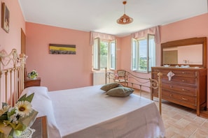 Un dormitorio con cama, cómoda y ventana con cortinas.