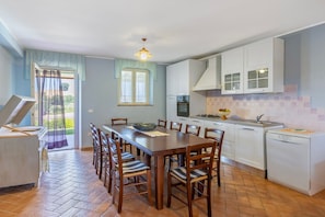 Cocina compacta con armarios blancos, una mesa de comedor con sillas y un lavavajillas pequeño.