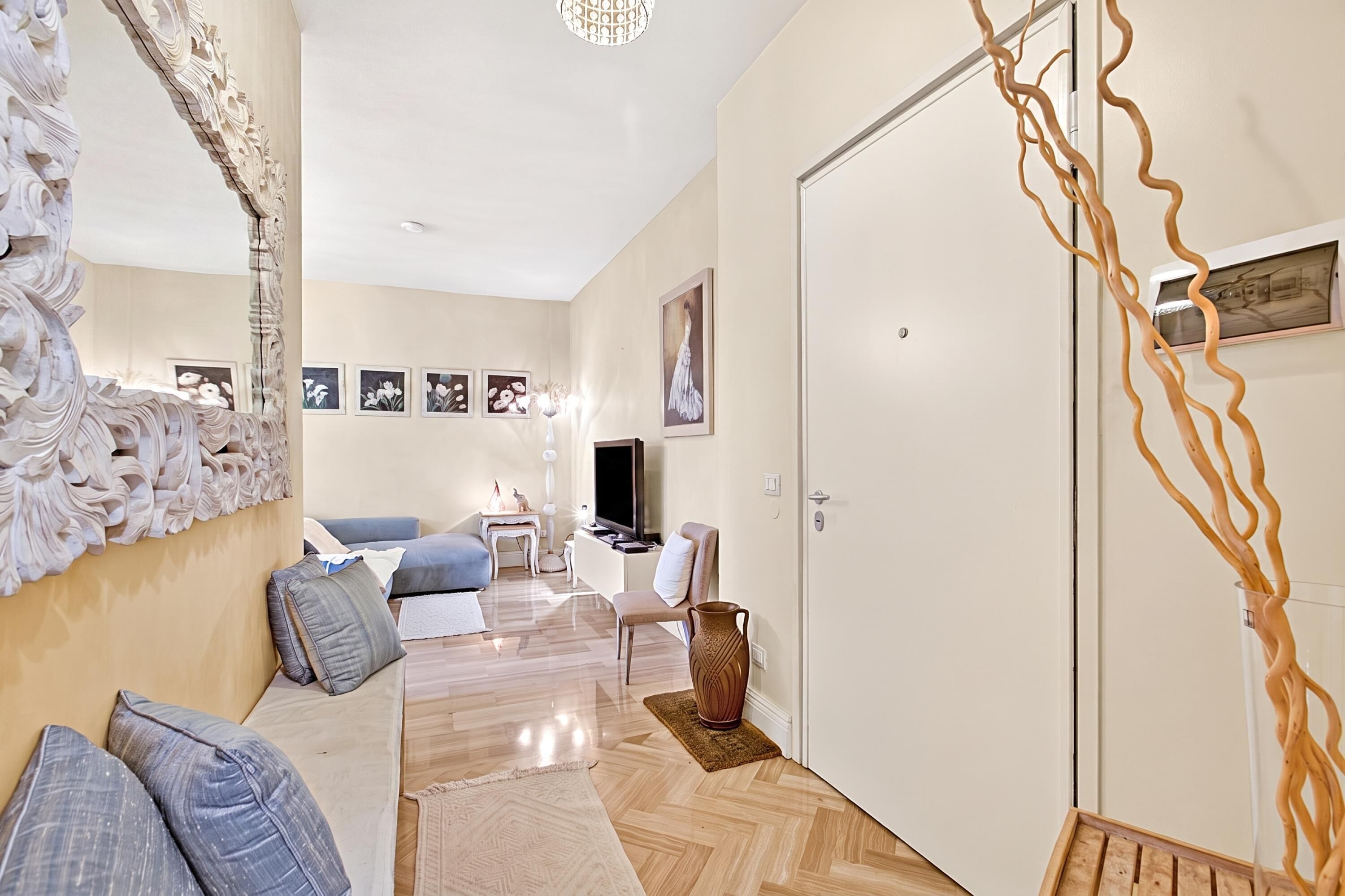 Un salon moderne avec un canapé, un téléviseur et un miroir décoratif.