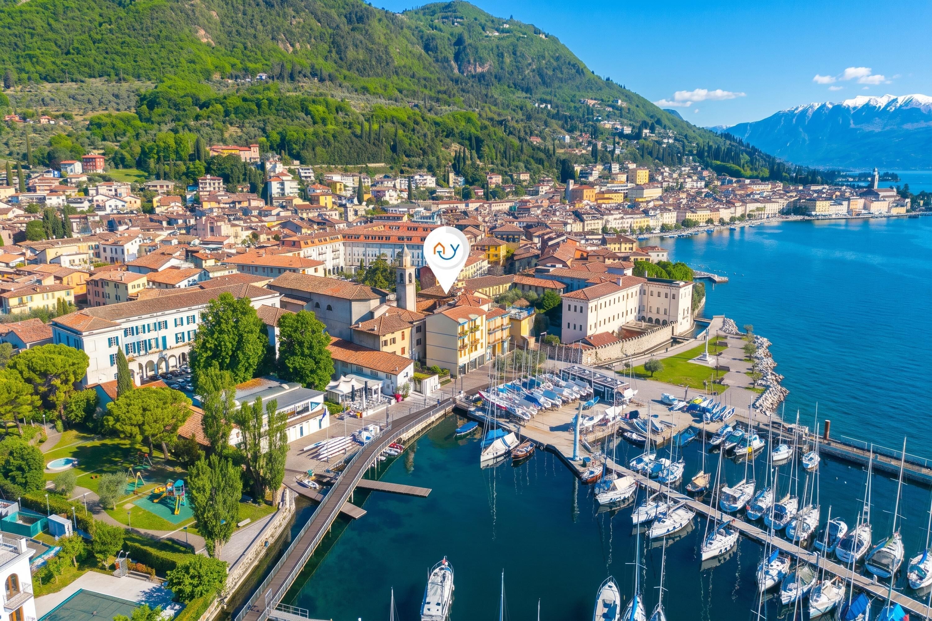 A coastal town with a marina, historic buildings, and a mountainous backdrop.