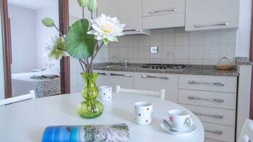 A kitchen with white cabinets, a granite countertop, and a dining table with a vase of flowers.