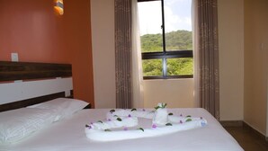 Une chambre d’hôtel avec un lit, une fenêtre avec des rideaux et une vue sur la verdure.
