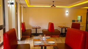 Un restaurant avec des banquettes et des tables, dont certaines sont dotées de coussins rouges.