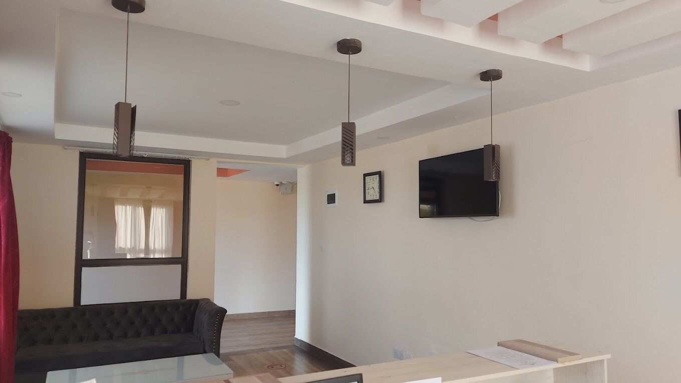 Una sala de estar moderna con un sofá oscuro, una mesa de centro de vidrio y un televisor montado.