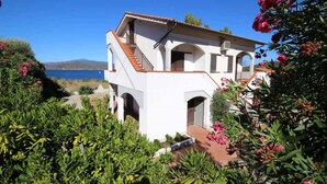 Eine weiße Villa mit rotem Ziegeldach, einer Treppe und Blick aufs Meer.