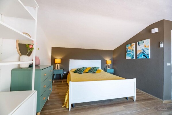 A bedroom with a bed, two bedside tables, a dresser, and artwork on the walls. - La Turistica - La Turistica - Mono Mansardato (Capoliveri)