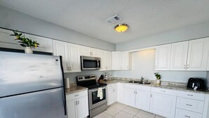 Een moderne keuken met witte kasten, roestvrijstalen apparatuur en een betegelde vloer.