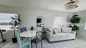 Een moderne woonkamer met een witte bank, een eettafel met stoelen en een kroonluchter.
