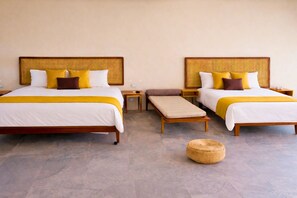 A hotel room with two beds, each with a woven headboard, white bedding, and yellow accents. There are bedside tables, a bench, and a woven basket on the floor. - Xperience Tulum Penthouse (Tulum)