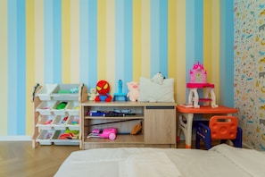 A child's room with a bed, a desk with toys, and a bookshelf.