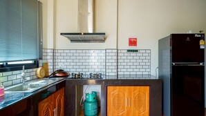 Eine moderne Küche mit Gaskochfeld, Backofen, Spüle aus Edelstahl und Holzschränken.