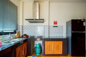Ett modernt kök med en gasspis, en inbyggd ugn, en diskho i rostfritt stål och träskåp.